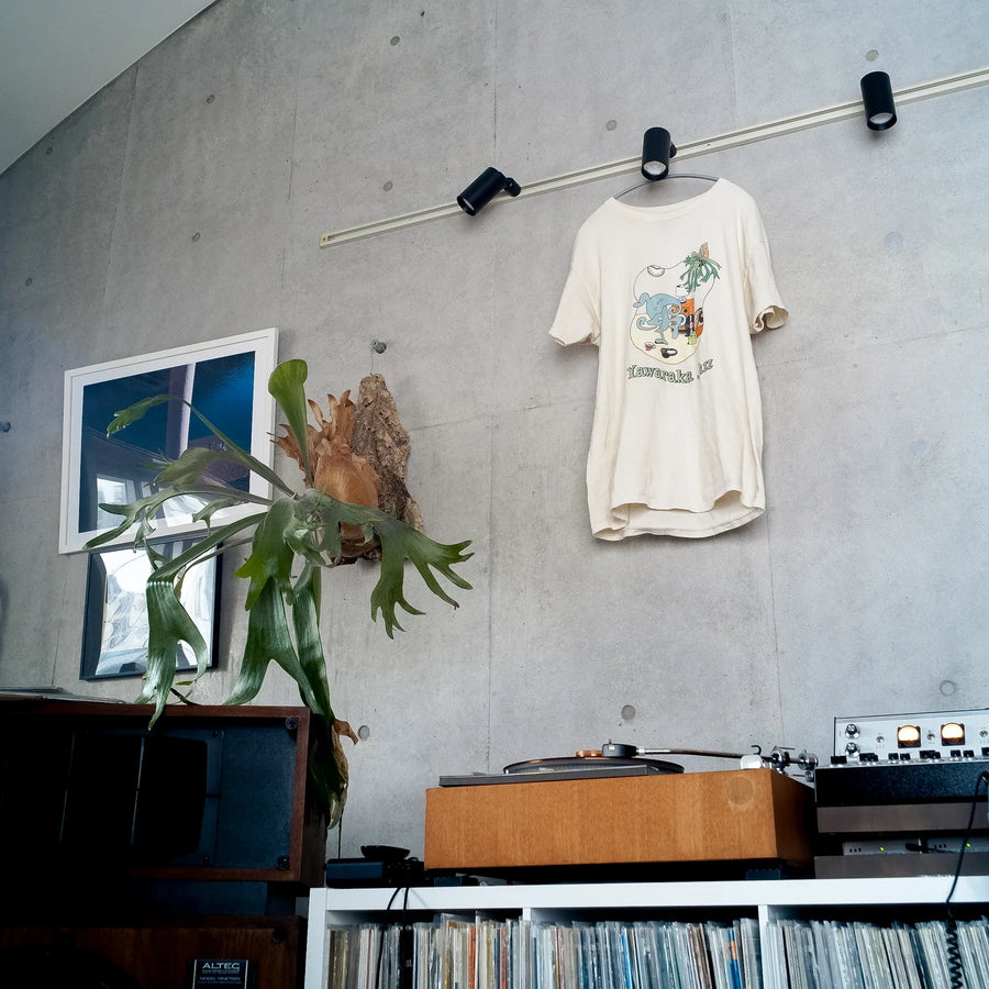Room Tee hanging on the wall of the room, above the records (photo shows the US-printed Room Tee)